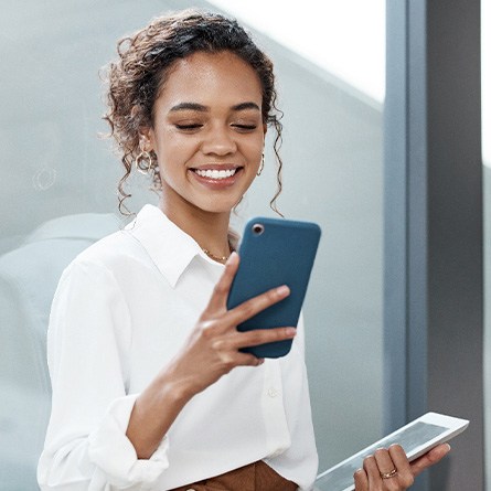 Woman smiling while looking at phone in office