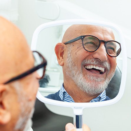 Man in glasses smiling in reflection in treatment chair