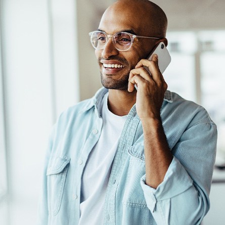 Man with glasses smiling while talking on phone