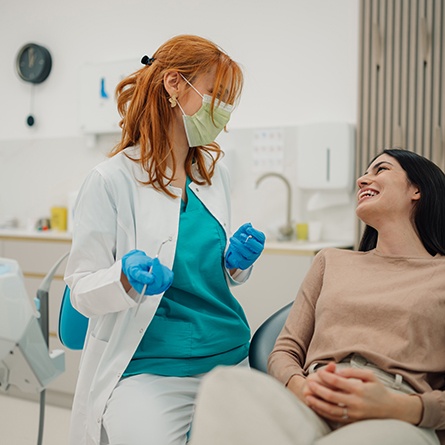 Woman smiling at reflection in handheld mirror