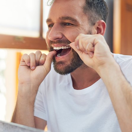 Patient flossing his teeth in bathroom