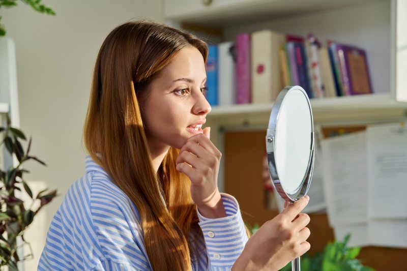 Patient with veneers checking teeth in mirror
