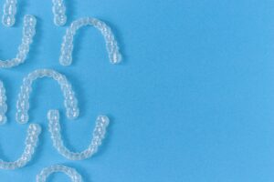 Several clear aligners against blue background.